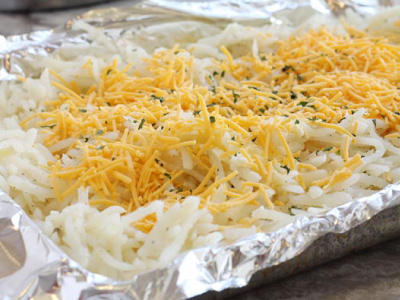 Uncooked hash browns prepped and on a aluminum foil on the baking sheet.