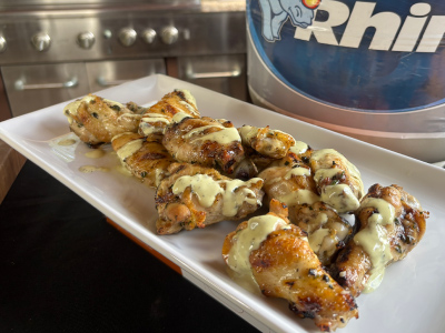 Finished Smoked Margarita Wings on a white plate, with a fresh Blue Rhino propane tank and standup propane grill in the background.
