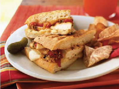 Finished sandwich cut in half and stacked on a white plate, sitting on a red plate.