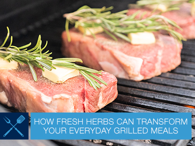 Three steaks with thyme on them sitting on the cooking grids of a standup propane grill.