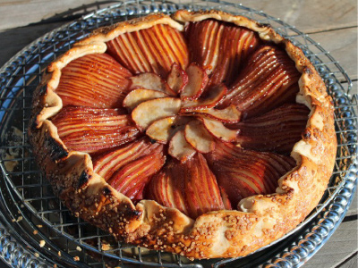 Finished poached pear galette on a cooling rack on a wood table.