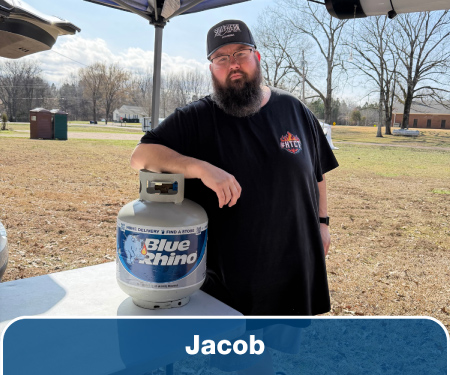 A man leaning on a Blue Rhino tank sitting on a table.