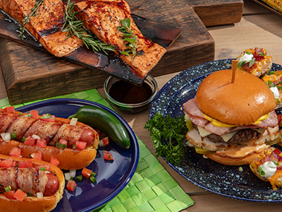 Finished Cuban Burger, Brats, and salmon filets on a table.