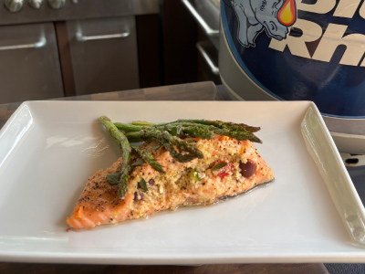 Finished stuff salmon on a white plate, with a fresh Blue Rhino and standup propane grill in the background.