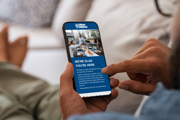 Man sitting on a couch reading a Blue Rhino email on a mobile phone.
