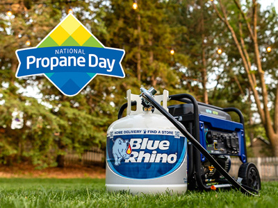Blue Rhino tank connected to a propane generator sitting in the grass in front of a house.