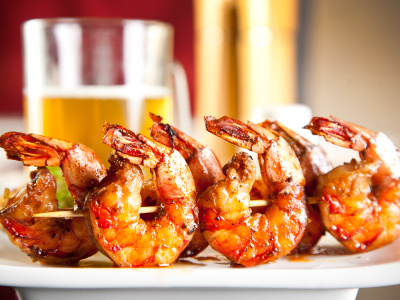 Grilled shrimp on wood skewers on white plates