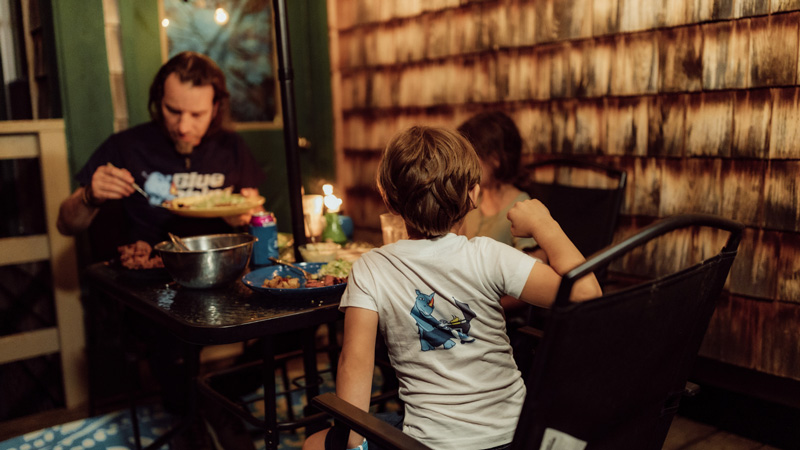 Family sitting around a table eating food, wearing Blue Rhino apparel.