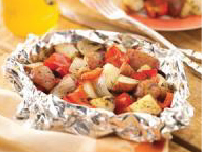 Grilled vegetables in an aluminum pouch on a wood table.