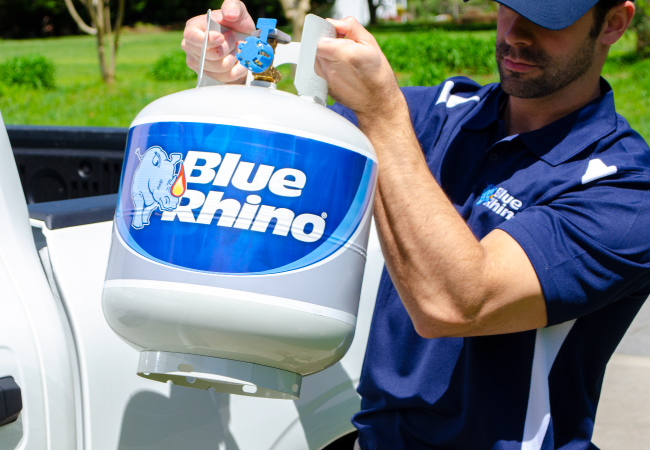 A Blue Rhino Delivery+ driver picking up a fresh Blue Rhino out of of a white pickup truck.