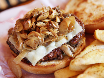 Finished grilled burger with french fries on parchment paper.