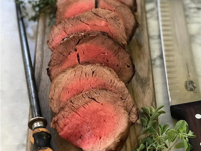 Slices of grilled tenderloin on a wood serving platter.