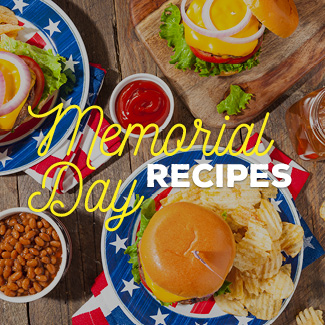 Top view of cheeseburgers and baked beans on American flag plates on a wooden table.