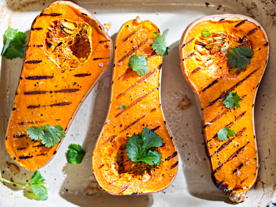 Three halves of grilled butternut squashes on a white plate.