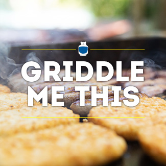 Closeup of hash browns and sausage links cooking on a propane griddle.