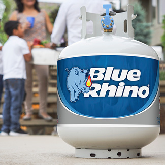 A fresh Blue Rhino tank on a patio with a family standing next to a standup propane grill in the background.