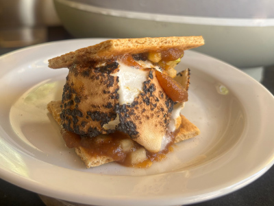 Finished apple pie s'more on a white plate with a fresh Blue Rhino tank in the background.
