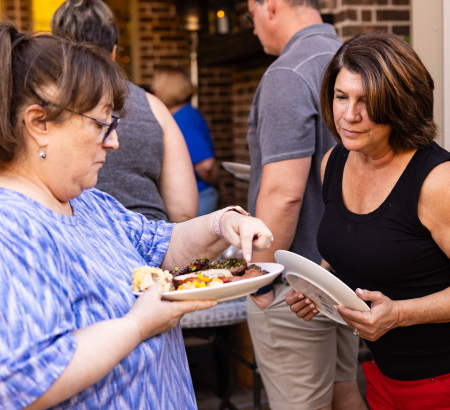 Chief Grilling Officer showing other party guest the food on a plate.