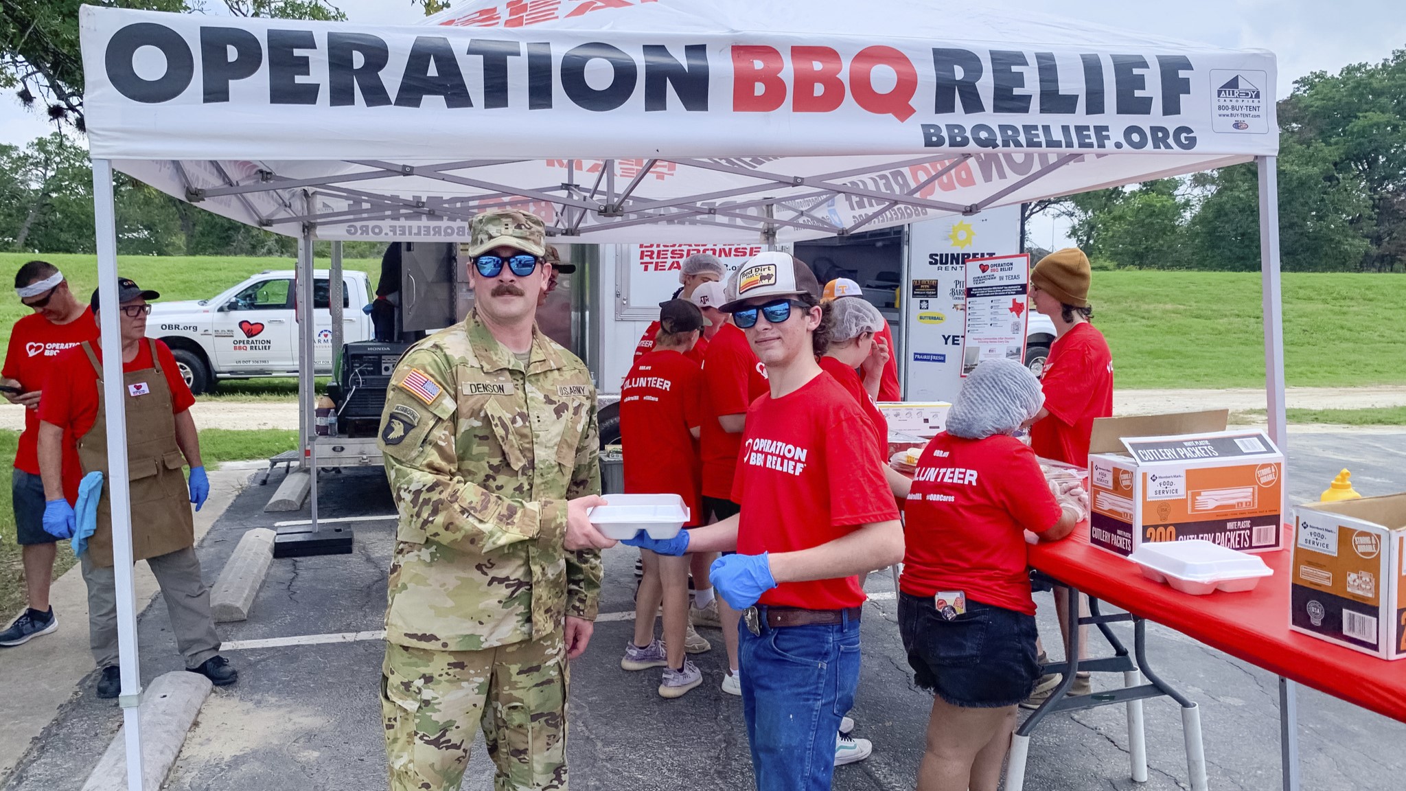 An OBR volunteer serving a meal to a military personel with other OBR volunteer in the background.
