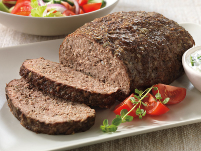 Finished meatloaf and sliced sitting on a white plate.