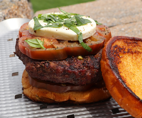 Closeup of a finished burger on a steel plate.
