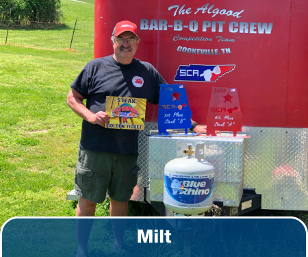 A man standing in front of a red trailer with a Blue Rhino tank in the forground.