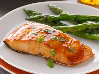 Grilled salmon filet with grilled asparagus, on a white plate.