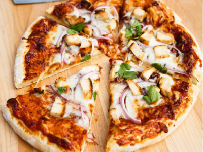 Finished pizza cut into slices, sitting on a wood table.