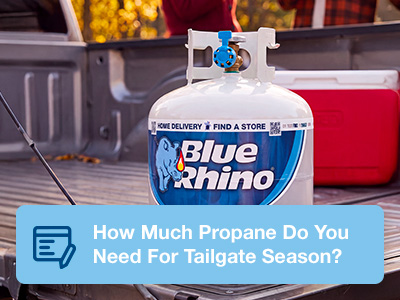 A fresh Blue Rhino tank sitting on the back of a pickup's tailgate, with a cooler and people in the background.