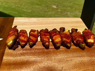 Finished Bacon Wrapped Jalapeños on a wooden cutting board.
