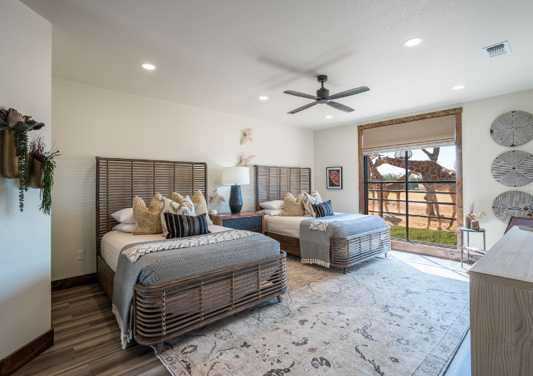 Longneck Manor's private villa, with two queen beds and a window with giraffes in the background.