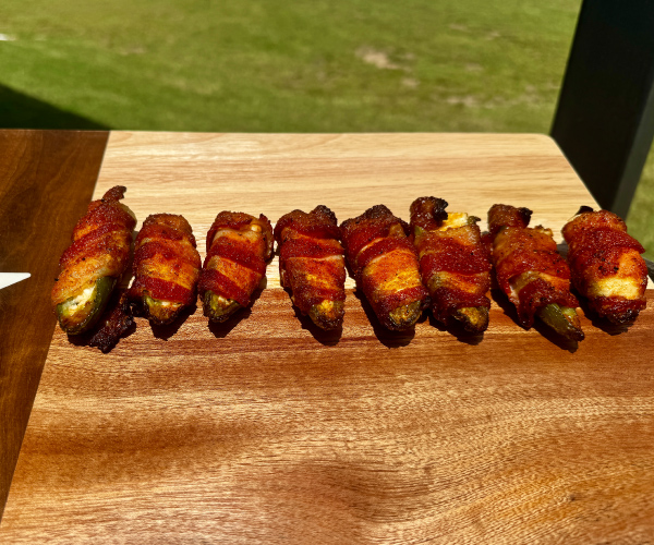 Finished Bacon Wrapped Jalapeños on a wooden cutting board.