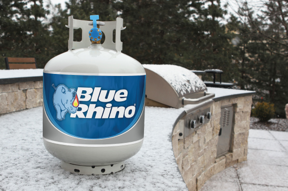 Blue Rhino tank sitting on a built-in propane grill's countertop, covered in snow.