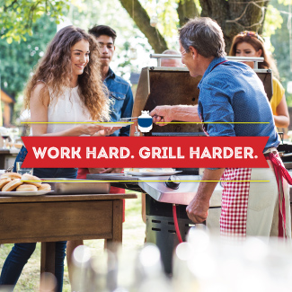 In a backyard, a man wearing an apron, serving food from a standup propane grill.