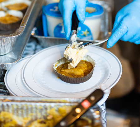 Chef topping ice cream onto freshly smoked cupcakes, sitting on a white plates.