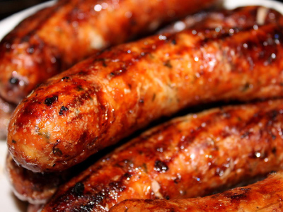 Stack of grilled brat on a white plate.