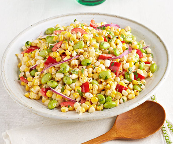 Finished edamame and grilled corn salad in a white bowl, sitting on a white table.