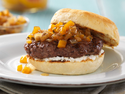 Finished burger on a white plate, sitting on a tank napkin on a blight blue wood table.