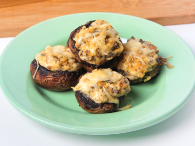 Four finished mushrooms on a light green plate on a wooden table.