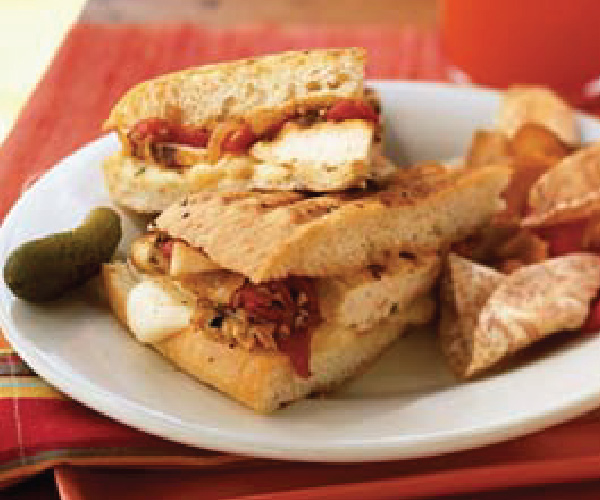 Finished sandwich cut in half and stacked on a white plate, sitting on a red plate.