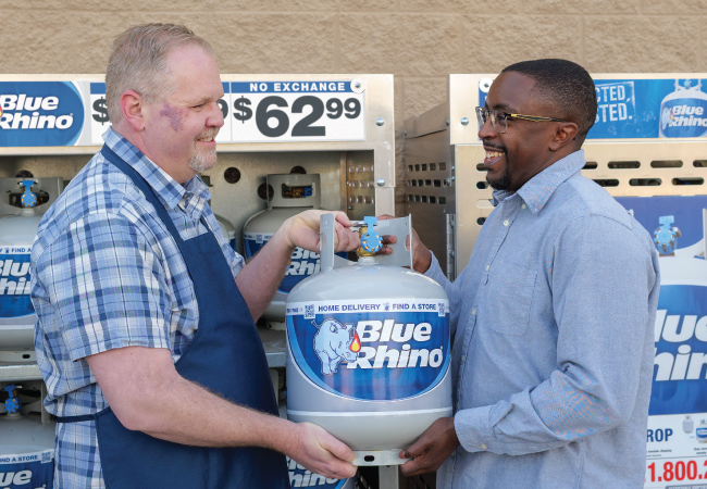 Retailer placing a fresh Blue Rhino in the hands of a customer, in front of a Blue Rhino display.