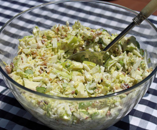 Finished Waldorf Slaw in a glass bowl on a black and white table cloth.
