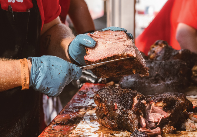 Operation BBQ Relief chef cutting up brisket.