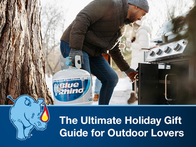 A man in winter attire placing a fresh Blue Rhino into standup propane grill.