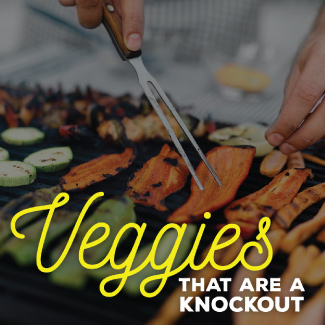 A man with a grilling fork, flipping over vegetable being grilled.