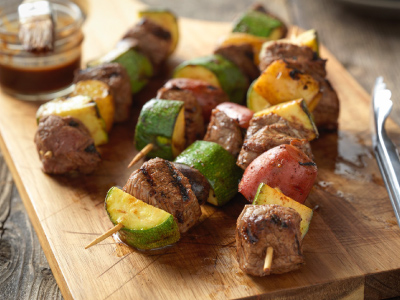 Grilled steak and potato kabobs on a wood cutting board.